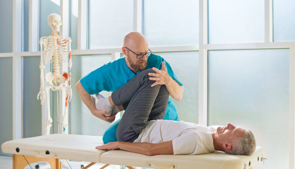 An Adult Man Trains Muscle Strength With a Professional Doctor in a Modern Rehabilitation Clinic. Physiotherapy Program, Rehabilitation After Medical Injuries. Healthcare Concept