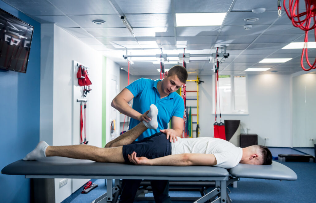 Rehabilitation therapy. Physiotherapist working with young male patient