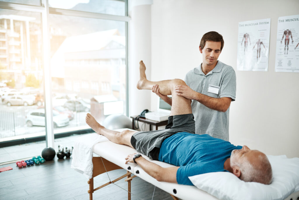Stretching legs, mature man and physiotherapist with fitness  in clinic for physical therapy, support or mobility exercise. Health, male doctor and patient for help, muscle recovery or rehabilitation.